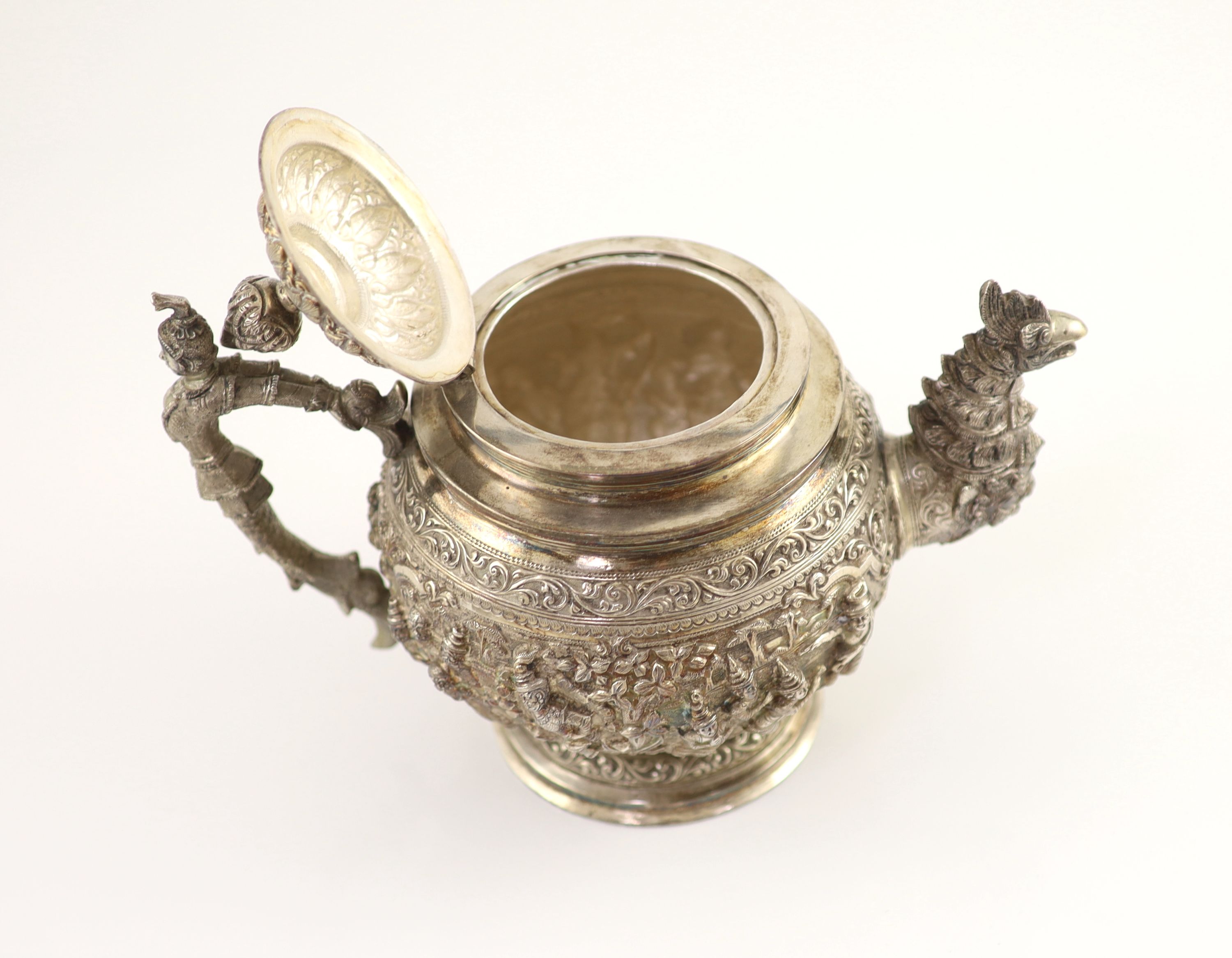 An impressive Burmese Sterling silver (950) three-piece tea service, with tray, cast with figures, teapot with cockerel spout and figural handle